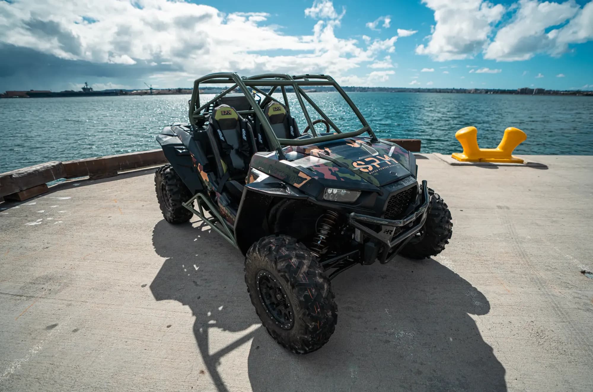 Three-quarter view of the SPM Alpha Prototype electric UTV, olive drab roll cage and camouflage bodywork